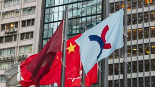 The flag (R) of the Hong Kong Exchanges and Clearing Limited (HKEX) is hoisted next to China’s flag (C) in Hong Kong on August 16, 2016.