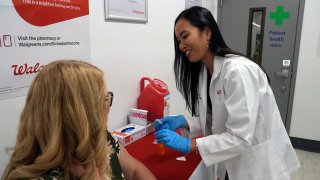 Anh Nguyen prepares to administer a COVID-19 vaccine for Kelly Vazquez at a pharmacy in New York, Sept. 24, 2024.