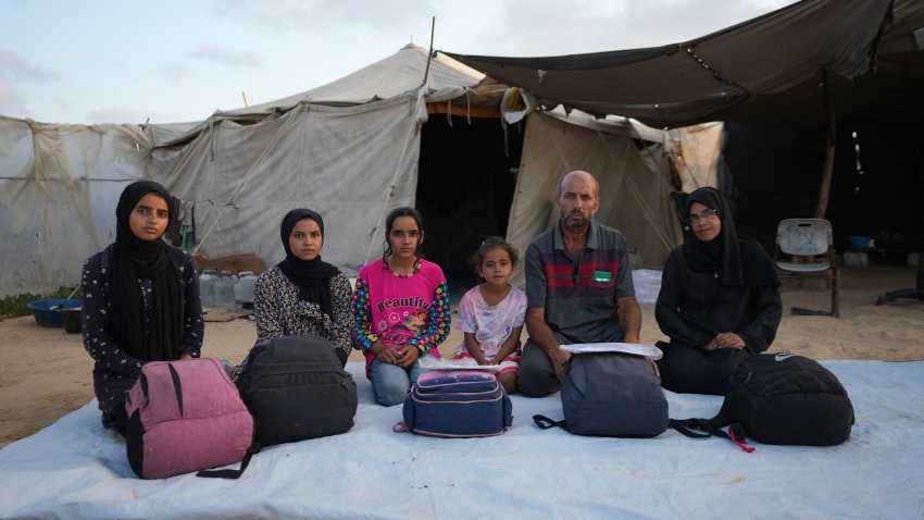 Members of the Abu Jarad family pose for a photo in their tent camp, where they now live after being displaced over five times since the start of the Israel-Hamas war, in Muwasi, Gaza Strip, Friday, Sept. 13, 2024.