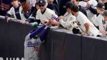 Fans interfere with a foul ball caught by Los Angeles Dodgers right fielder Mookie Betts during the first inning in Game 4 of the baseball World Series against the New York Yankees, Tuesday, Oct. 29, 2024, in New York. (AP Photo/Ashley Landis)