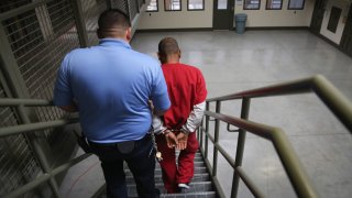 A guard escorts an immigrant detainee from his ‘segregation cell’ back into the general population at the Adelanto Detention Facility, managed by GEO Group.