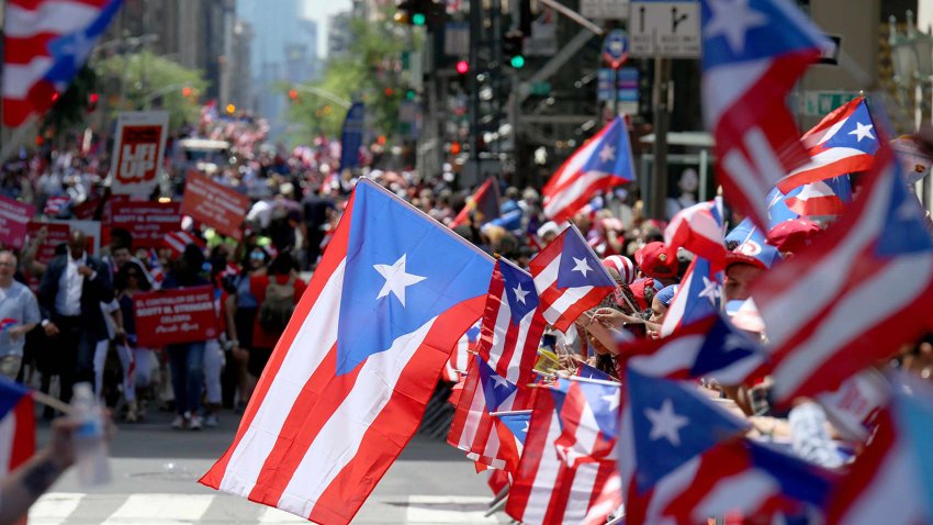 Parade attendees wave Puerto Rican flags on Fifth Avenue in Manhattan during the annual Puerto Rico Day Parade. 