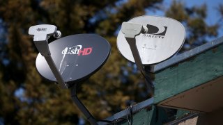 A Dish Network satellite dish (L) is mounted next to a DirecTV dish on the roof of an apartment building on April 15, 2013 in San Rafael, California. 