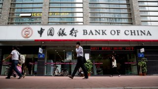 A man on a mobile phone walks past a Bank of China Ltd. branch in Guangzhou, Guangdong Province, China, on Thursday, March 27, 2014.