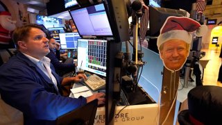 An image of US President-elect Donald Trump is displayed as traders and financial professionals work on the floor of the New York Stock Exchange (NYSE) at the opening bell on November 26, 2024, in New York City.