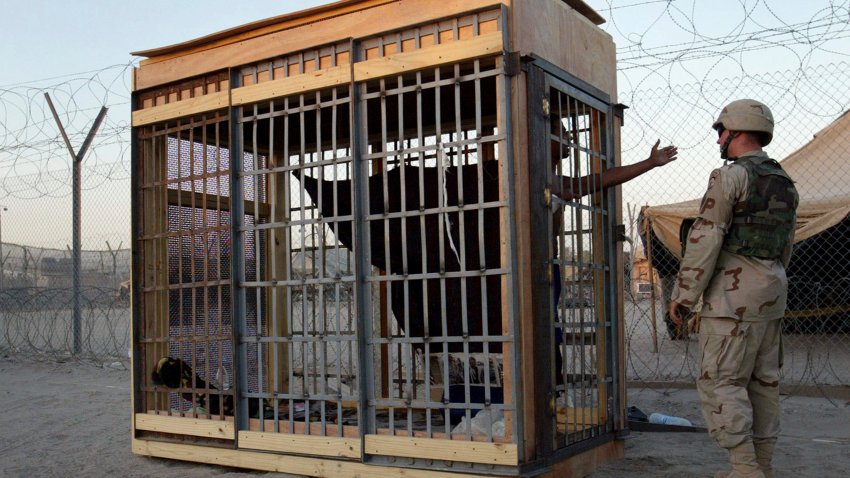 FILE - A detainee in an outdoor solitary confinement cell talks with a military police officer at the Abu Ghraib Prison on the outskirts of Baghdad, Iraq, June 22, 2004.