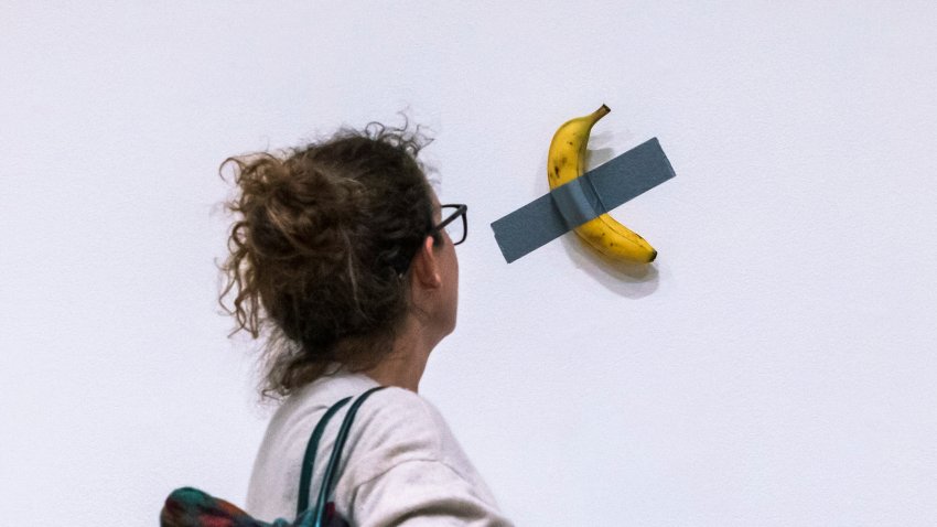 File – A woman looks at artist Maurizio Cattelan’s piece of art “Comedian” during an auction preview at Sotheby’s in New York, Monday, Nov. 11, 2024.