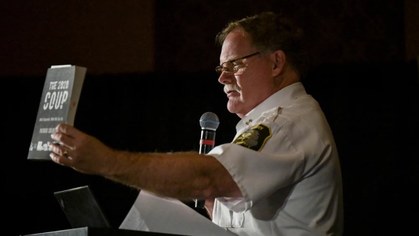 Barry County Sheriff Dar Leaf, from Michigan, with a book titled “The 2020 Coup” during a press conference in Las Vegas in 2022