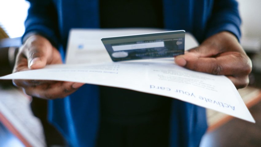Close-up of unrecognizable black woman opening mail containing new credit card