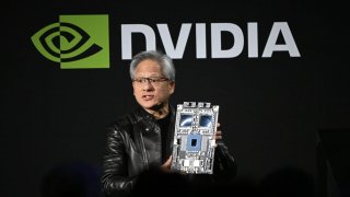 Jensen Huang, co-founder and CEO of Nvidia Corp., holds up the company’s AI accelerator chips for data centers as he speaks during the Nvidia AI Summit Japan in Tokyo on Nov. 13, 2024.