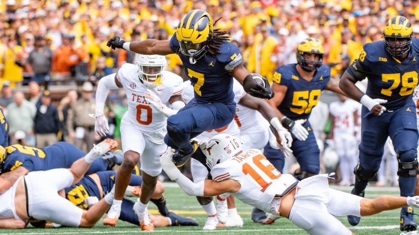 Donovan Edwards #7 of the Michigan Wolverines hurdles a tackle attempt by Michael Taaffe #16 of the Texas Longhorns during the first half of a college football game at Michigan Stadium on September 07, 2024 in Ann Arbor, Michigan.