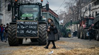 A woman walks past a tractor bearing a sign that reads “Do we have the right to a future” in front of the Burgundy Regional Council during farmers’ protest against the consequences of government censorship and EU-Mercosur agreement, in Dijon, central eastern France on December 11, 2024.