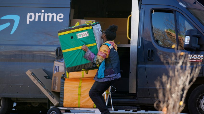 FILE – An Amazon Prime delivery person lifts packages while making a stop on Nov. 28, 2023, in Denver. (AP Photo/David Zalubowski, File)