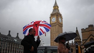 Pedestrians shelter from the rain under umbrellas as they pass the Elizabeth Tower, commonly known by the name of the clock’s bell, Big Ben, at the Palace of Westminster, home to the Houses of Parliament, in London on Feb. 22, 2024.