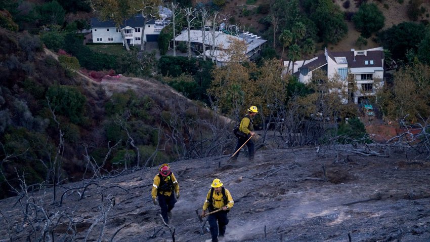 Firefighters near burn scars in the aftermath of the Palisades Fire in the Mandeville Canyon neighborhood of Los Angeles, California, US, on Sunday, Jan. 12, 2025.