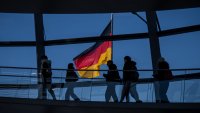 19 February 2025, Berlin: Visitors walk in front of the German flag in the dome of the Bundestag. 