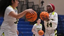 Lesley University basketball player Baileigh Sinaman-Daniel, right, lines up a shot while practicing prior to game Tuesday, Feb. 11, 2025, in Lexington, Mass. (AP Photo/Charles Krupa)