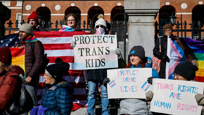 Demonstrators hold signs supporting transgender rights