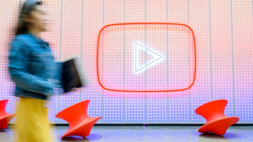 People walk by a YouTube logo as Google celebrates the 20th anniversary of the first video uploaded to YouTube, at the company’s corporate headquarters in San Bruno, California, on April 23, 2025.
