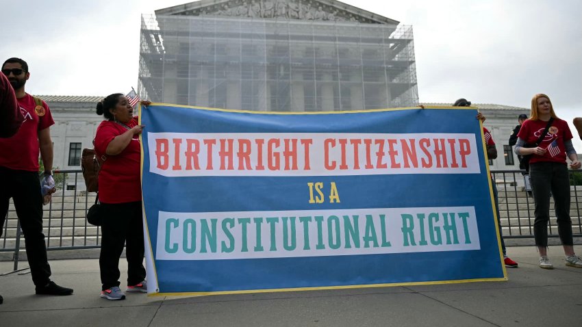 People hold a sign as they participate in a protest outside the U.S. Supreme Court over President Donald Trump’s move to end birthright citizenship as the court hears arguments over the order in Washington, May 15, 2025.