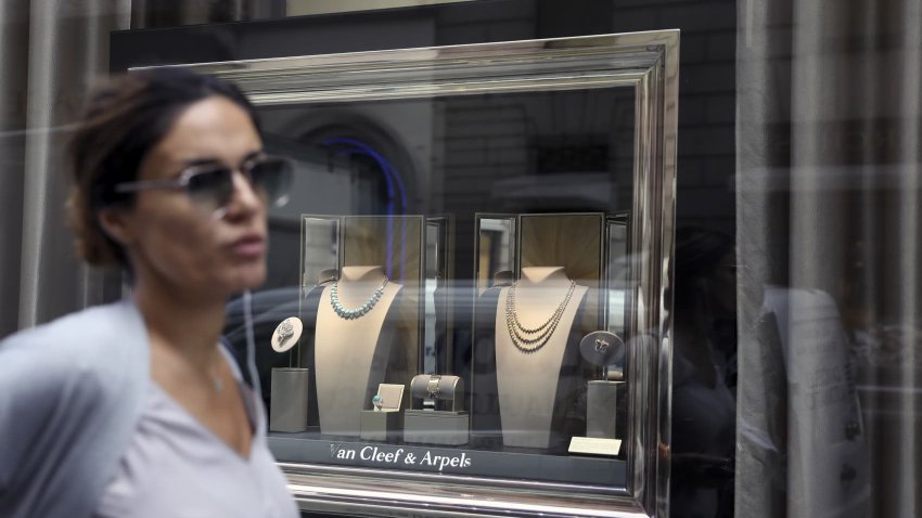 A shopper passes a jewelry display in the window of a Van Cleef & Arpels luxury goods store, operated by Cie. Richemont SA, on via Montenapoleone in Milan, Italy.