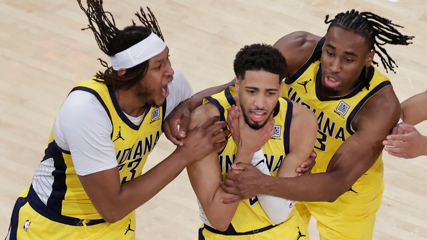Indiana Pacers guard Tyrese Haliburton (0) is mobbed by teammates as he makes a choking motion after hitting a shot against the New York Knicks at the end of regulation to tie Game 1 of the NBA basketball Eastern Conference final, Wednesday, May 21, 2025, in New York.