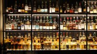 Various whiskey bottles on shelves in a bar.