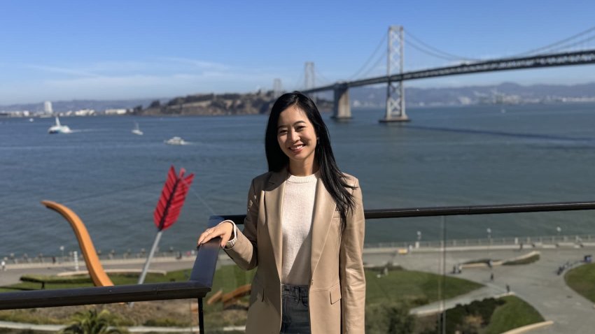 Janet Lee, who spends Wednesday through Friday in San Francisco, poses in front of the Bay Bridge.