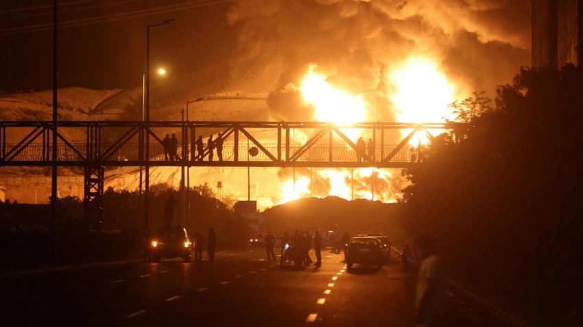 People watch from a bridge as flames from an Israeli attack rise from Sharan Oil depot, following Israeli strikes on Iran, in Tehran, Iran, June 15, 2025.