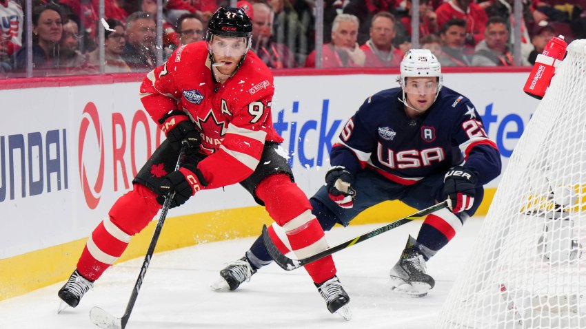 Connor McDavid of Team Canada passes the puck as Charlie McAvoy of Team USA looks on