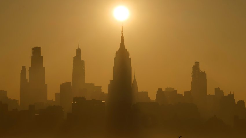 JERSEY CITY, NJ – JUNE 19: The sun rises behind the skyline of midtown Manhattan and the Empire State Building in New York City, a day ahead of the summer solstice and an expected heatwave on June 19, 2025, as seen from Jersey City, New Jersey.  (Photo by Gary Hershorn/Getty Images)