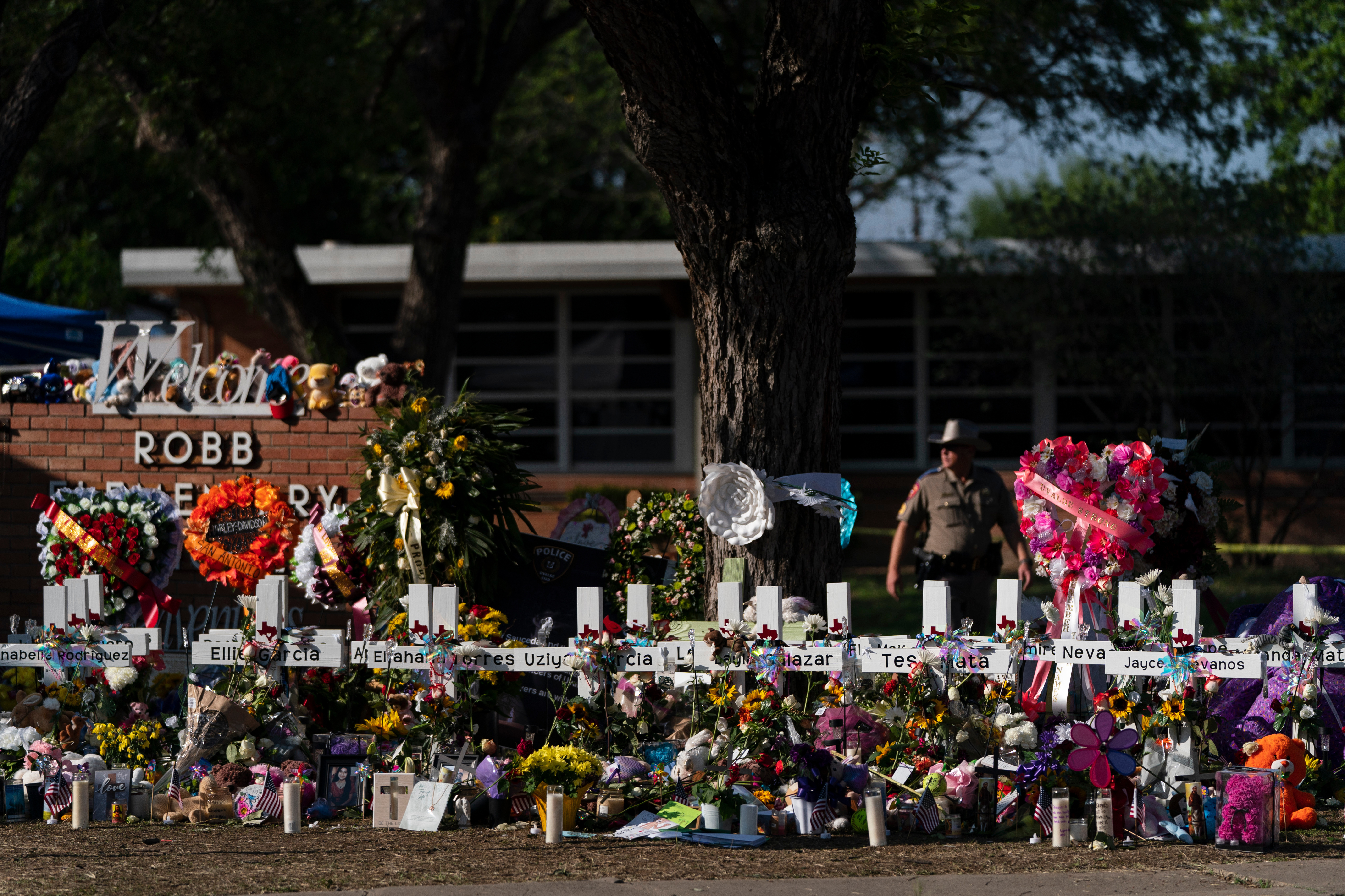 FILE - Flowers and candles are placed around crosses to honor the victims killed in a school shooting, May 28, 2022, outside Robb Elementary School in Uvalde, Texas.