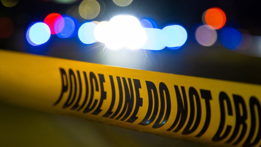 A crime scene in a city at night with yellow police tape.