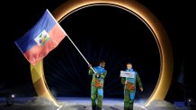 Flagbearer Stevenson Savart of Team Haiti enters with his teammate into the stadium during the opening ceremony of the Milano Cortina 2026 Winter Olympics at Predazzo Ski Jumping Stadium on February 06, 2026 in Val di Fiemme, Italy.