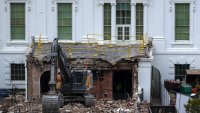 An excavator sits on the rubble after the East Wing.