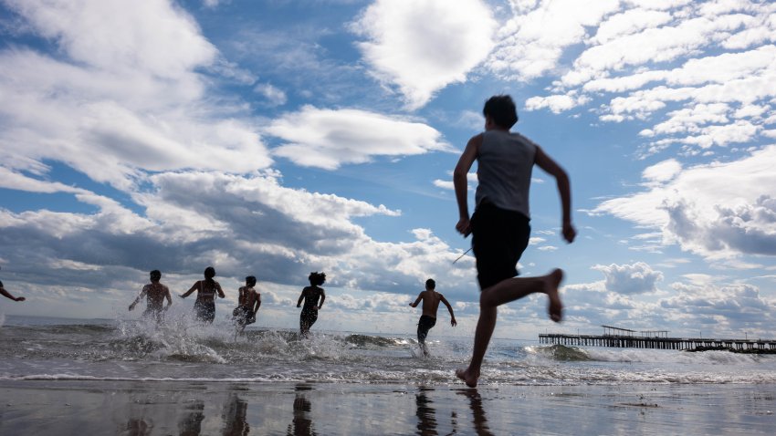 NEW YORK, NEW YORK – APRIL 01: A group of teens run into the ocean on a warm Spring afternoon at Coney Island in Brooklyn on April 01, 2026 in New York City. Coney Island, one of the nation’s oldest beach and amusement park communities, saw both Luna Park and Deno’s Wonder Wheel Amusement Park hold opening ceremonies last weekend as the area prepares for the busy beach season. (Photo by Spencer Platt/Getty Images)