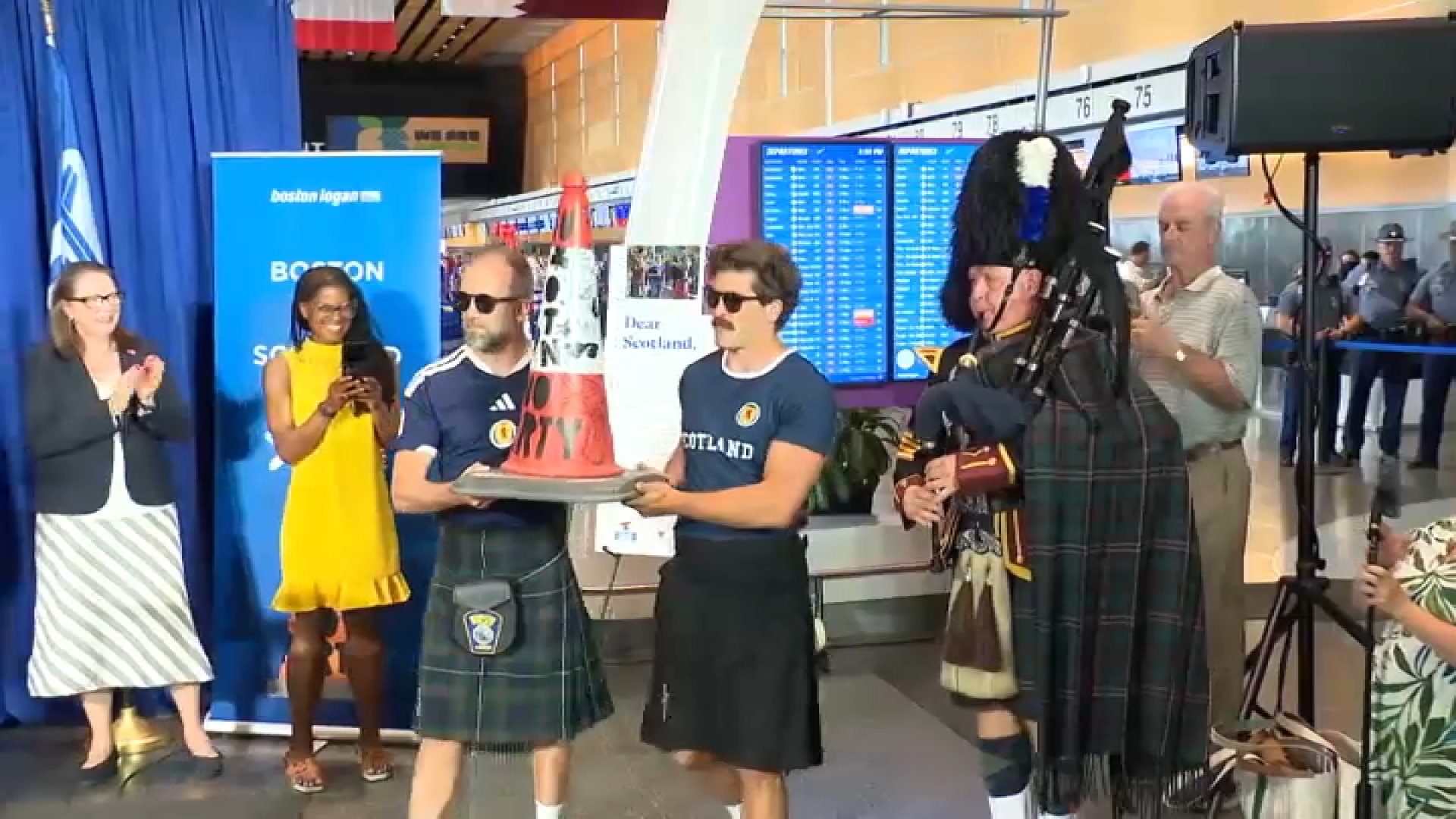 Andrew Dobbie and Danny Campbell carrying their "No Boston, No Party" traffic cone into a welcome ceremony at Boston Logan International Airport on Tuesday, July 14, 2026.